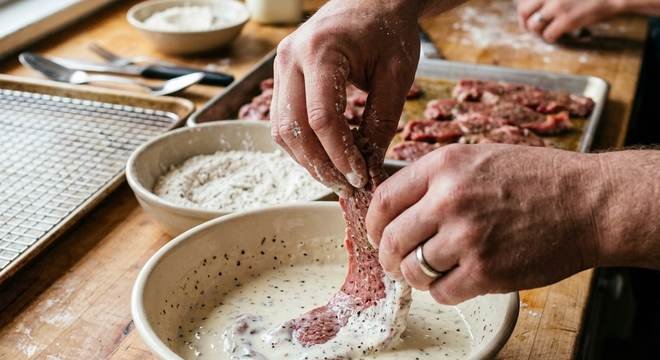 Dipping beef strips in buttermilk marinade for finger steaks